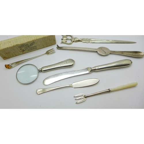 923 - A silver handled magnifying glass, two silver forks, a silver butter spreader, a letter opener, etc.