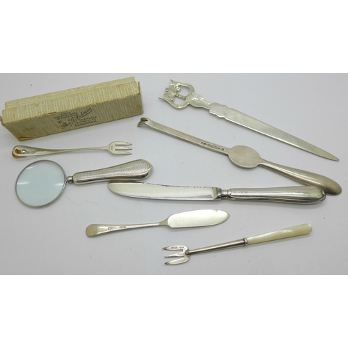 923 - A silver handled magnifying glass, two silver forks, a silver butter spreader, a letter opener, etc.