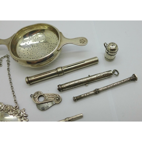 938 - A silver whisky label, a silver strainer, four pencils, a small silver pepper and a silver cutter