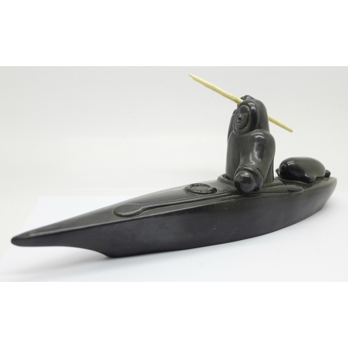 638 - A carved soapstone model of an Inuit in a canoe, 26.5cm