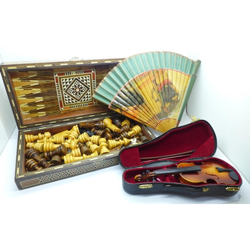 692 - A wooden chess set, a miniature violin and a fan