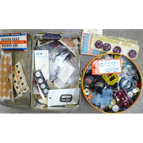 711 - A collection of vintage buttons and buckles in two tins including many sets on card