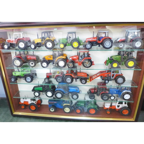 805 - A collection of 21 model tractors in a display case