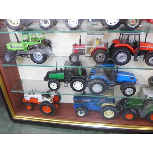 805 - A collection of 21 model tractors in a display case