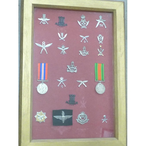 819 - A collection of Ghurka badges and two WWII medals in a display case