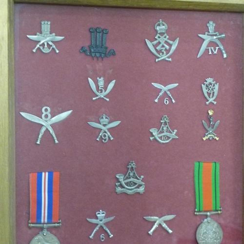 819 - A collection of Ghurka badges and two WWII medals in a display case