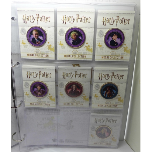 937 - A collection of 20 Harry Potter medals in a folder and one other folder with three character medals ... 