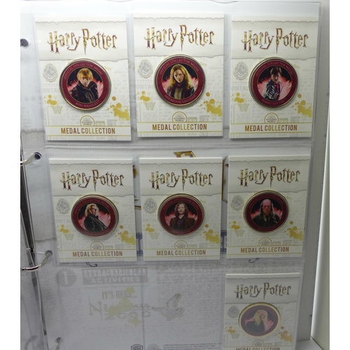 937 - A collection of 20 Harry Potter medals in a folder and one other folder with three character medals ... 