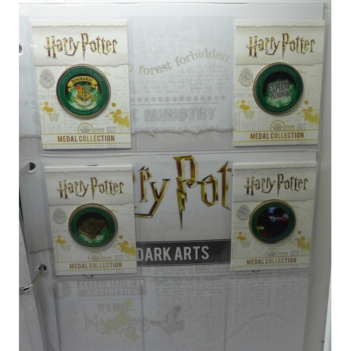 937 - A collection of 20 Harry Potter medals in a folder and one other folder with three character medals ... 