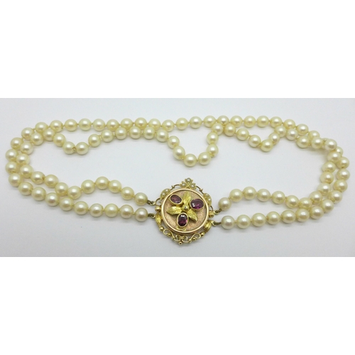 975 - A double row of cultured pearls with a 15ct gold clasp set with garnets, clasp 27mm x 33mm