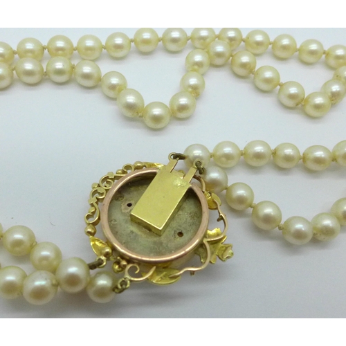 975 - A double row of cultured pearls with a 15ct gold clasp set with garnets, clasp 27mm x 33mm