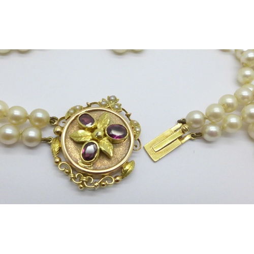 975 - A double row of cultured pearls with a 15ct gold clasp set with garnets, clasp 27mm x 33mm