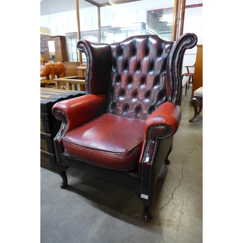 29 - A mahogany and red leather buttoned wingback armchair