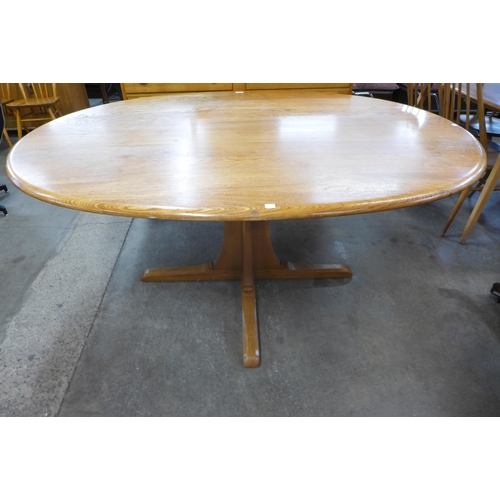 100 - An Ercol elm and beech pedestal dining table