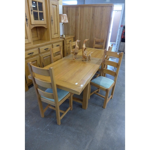 1557 - A French oak extending dining table and six ladderback chairs