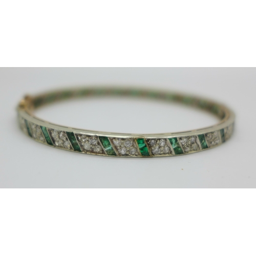 1056 - An Art Deco diamond and emerald set bangle with gold back and silver setting/front, the emeralds set... 