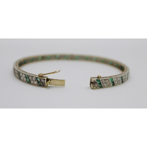 1056 - An Art Deco diamond and emerald set bangle with gold back and silver setting/front, the emeralds set... 