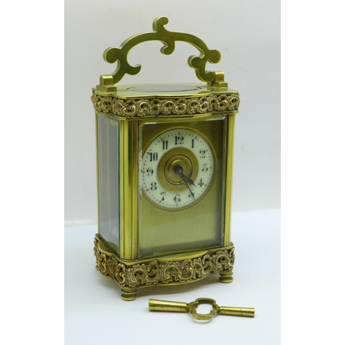632 - A French brass framed carriage clock with shaped base and top, with key
