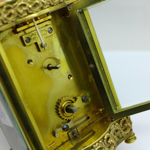 632 - A French brass framed carriage clock with shaped base and top, with key