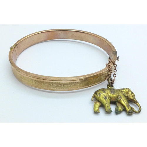 967 - A 9ct gold bangle, 8.7g, with a plated elephant charm