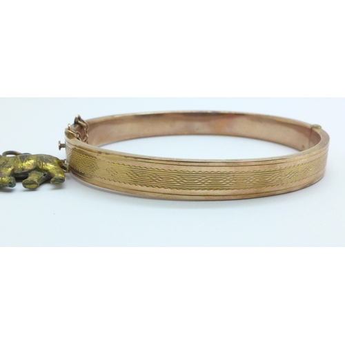 967 - A 9ct gold bangle, 8.7g, with a plated elephant charm