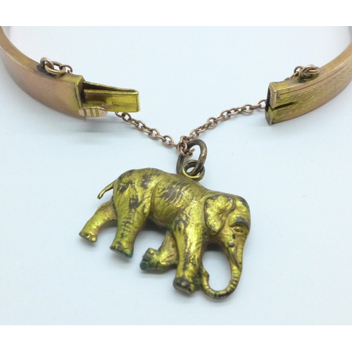 967 - A 9ct gold bangle, 8.7g, with a plated elephant charm