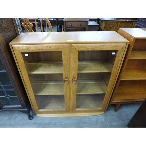 153 - An Ercol Blonde elm two door bookcase