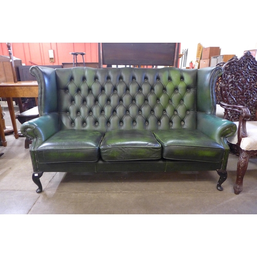 251 - A green leather Chesterfield wingback settee ( tear to seat cushion)