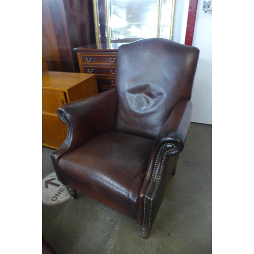 23 - A chestnut brown leather armchair and footstool