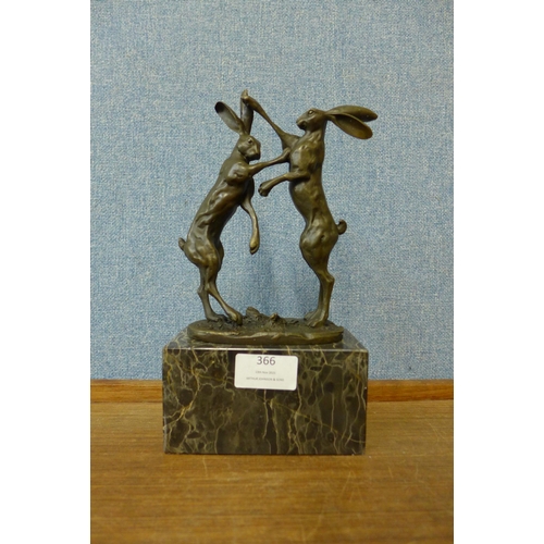 366 - A bronze figure of boxing hares, on black marble socle