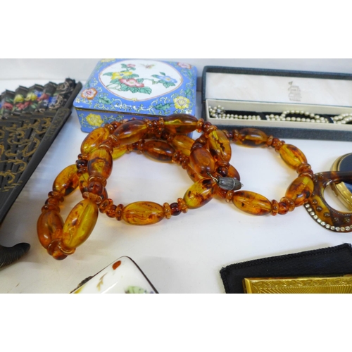 702 - Compacts, an enamel box, a string of amber coloured beads, etc.