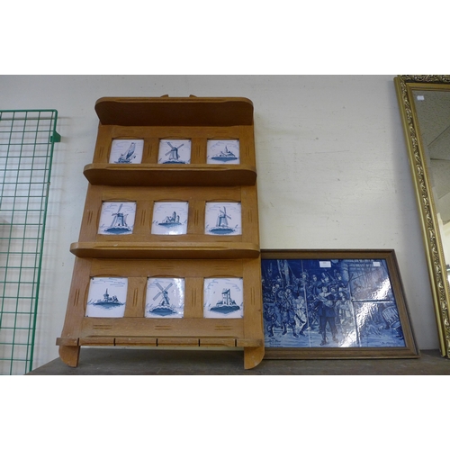 388 - An oak wall shelf inset with blue and white Delft tiles and a framed tiled plaque