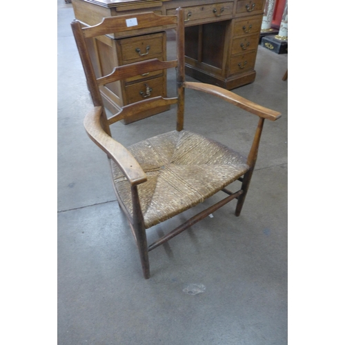 9 - An Arts and Crafts beech rush seated ladderback elbow chair, manner of Ernest Gimson