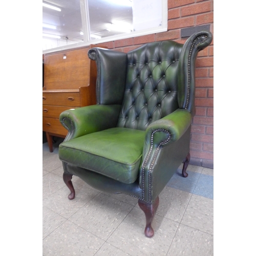 47 - A green leather Chesterfield wingback armchair