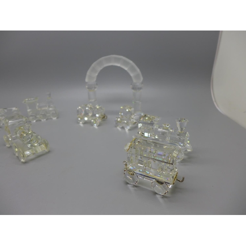 671 - A Swarovski crystal model train with arch and other glass model trains, with two stands