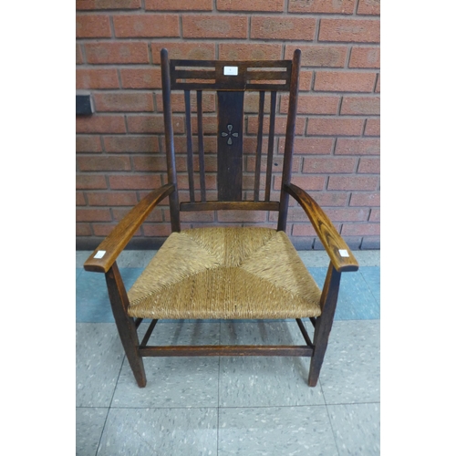 6 - An Arts and Crafts Liberty & Co. style oak rush seated elbow chair