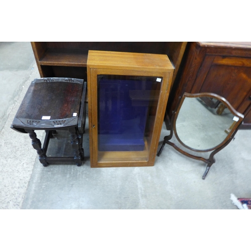 183 - A Victorian mahogany shield shape toilet mirror, a carved oak gateleg occasional table and a display... 