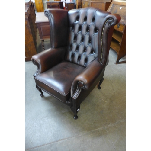 22 - A brown leather Chesterfield wingback armchair