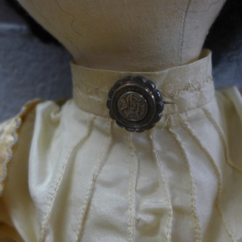 825 - A cloth Edwardian style boudoir doll in silk clothes and silver brooch, 54cm