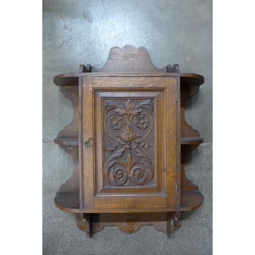 128 - An Edward VII carved oak wall hanging cabinet