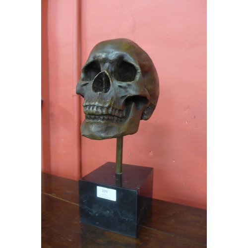 399 - A bronze skull, on black marble plinth