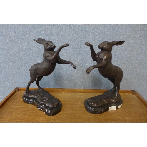 411 - A pair of bronze boxing hares, on black marble socles