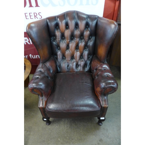 23 - A mahogany and chestnut brown leather Chesterfield wingback armchair