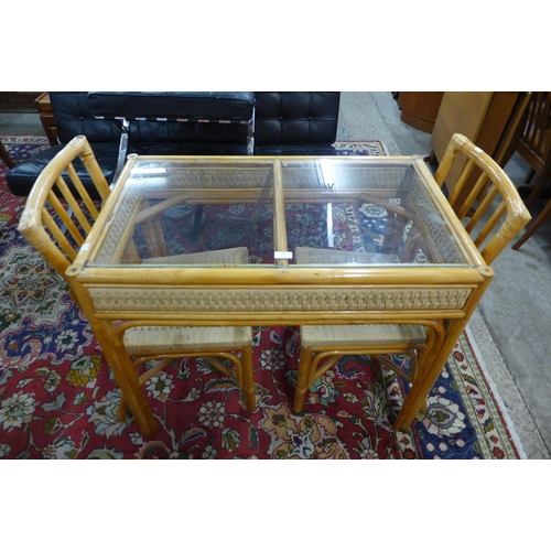 82 - A bamboo, wicker and glass topped table and two chairs