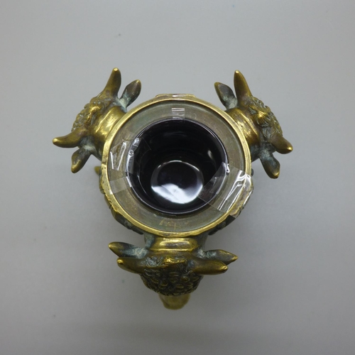 641 - A cast brass inkwell with three bull's heads and feet, lacking top