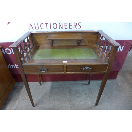 24 - An Arts and Crafts oak and green leather topped two drawer writing table