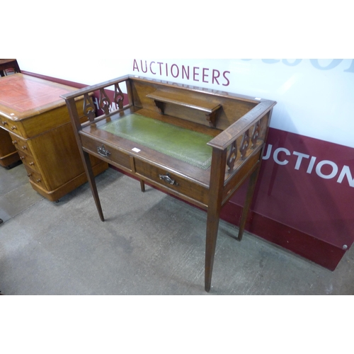 24 - An Arts and Crafts oak and green leather topped two drawer writing table