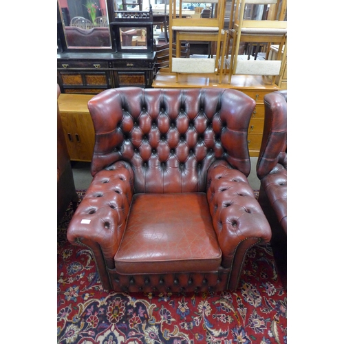 27 - A pair of oxblood red leather Chesterfield wingback armchairs