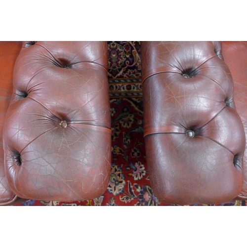 27 - A pair of oxblood red leather Chesterfield wingback armchairs