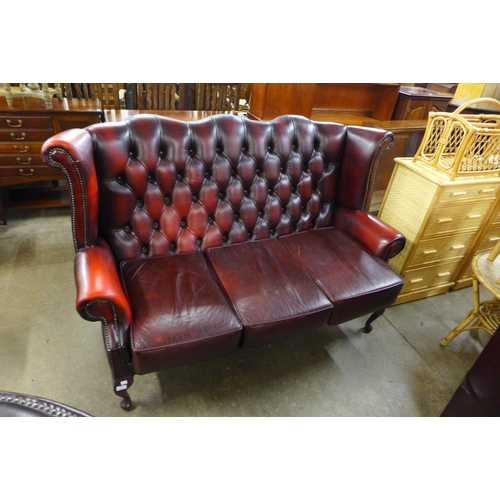 30 - A red leather Chesterfield wingback settee